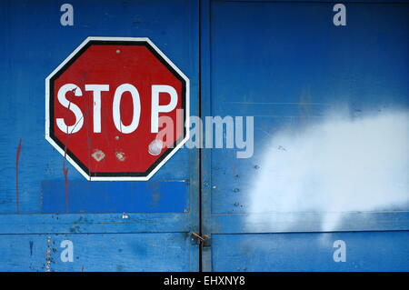 A Red Stop Sign on a Locked Blue Door of an Abandoned Warehouse with Copy Space Stock Photo