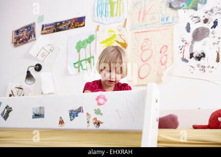 Little girl sitting on bunk bed, playing Stock Photo