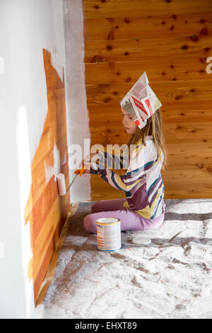 Girl painting wooden wall with paint roller Stock Photo
