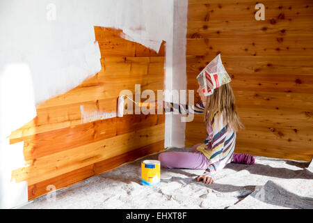 Girl painting wooden wall with paint roller Stock Photo