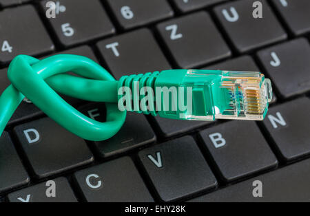 Network cable with green knot and keyboard. Stock Photo