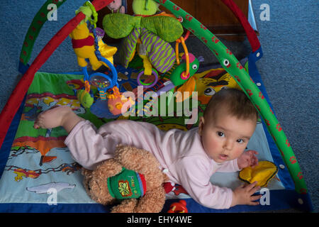 8 month old baby girl playing on floor with interactive toy Stock Photo