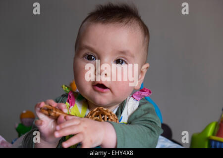 8 month old baby girl, surrounded by toys in baby bouncer, playing Stock Photo