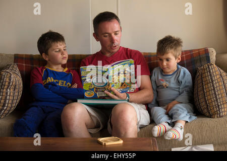 Father reading to his children on sofa at home Stock Photo