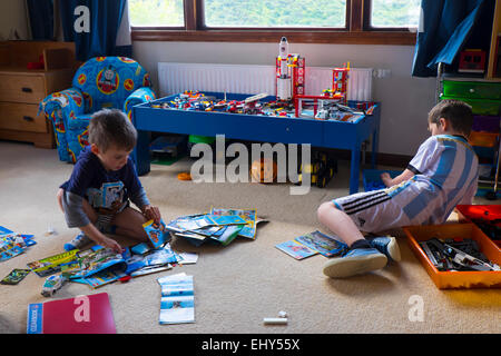 Brothers aged  aged four and six years playing with Lego building blocks in bedroom Stock Photo