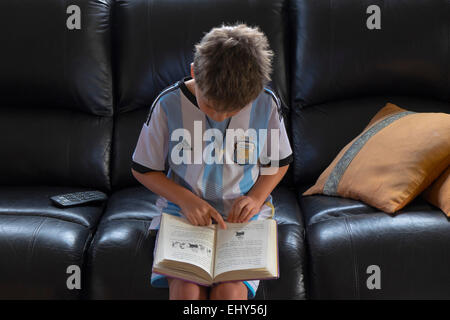 Six year old boy points to words in book as he learns to read Stock Photo