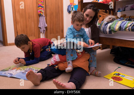 Girl reading to children in bedroom Stock Photo