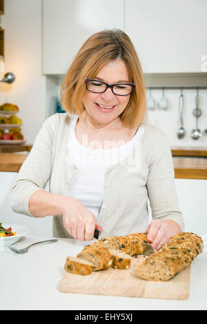 Senior woman cutting bread Stock Photo