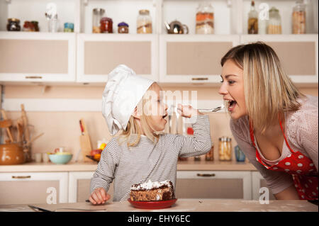 Little cute girl feeding her mother cake Stock Photo