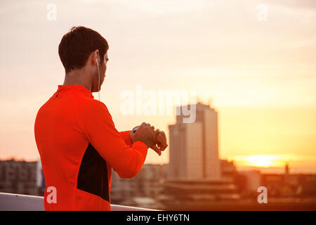 Male runner taking pulse at sunset Stock Photo