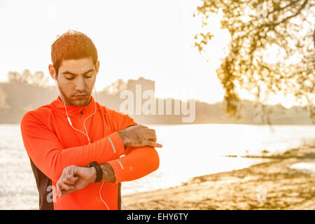 Male runner with headphones taking pulse Stock Photo