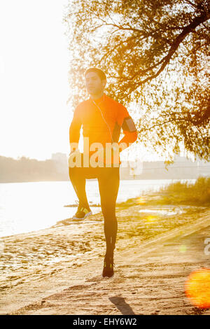 Male runner warming up on the waterfront at sunset Stock Photo