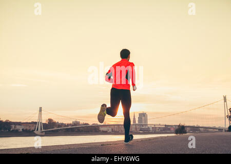 Man jogging on the waterfront against city skyline Stock Photo