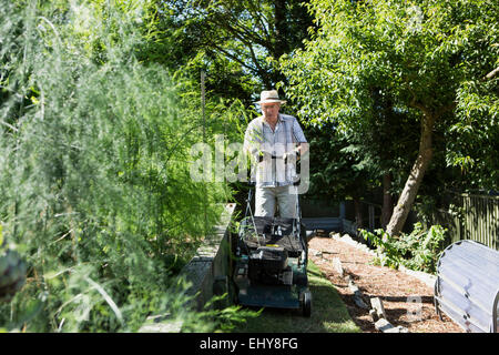 Senior man mows garden lawn, Bournemouth, County Dorset, UK, Europe Stock Photo