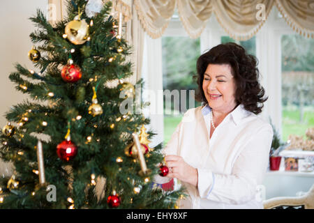 Senior woman decorating Christmas tree Stock Photo