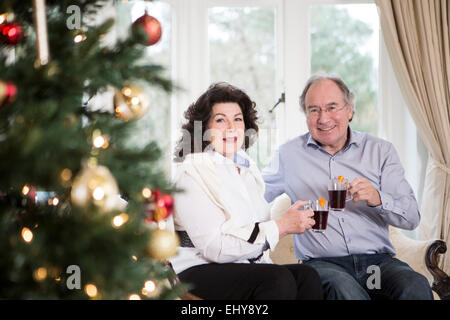 Senior couple drinking punch by Christmas tree Stock Photo