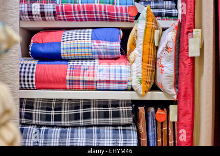 Bright pillows, plaids, blankets and other bedroom wear on shelves Stock Photo
