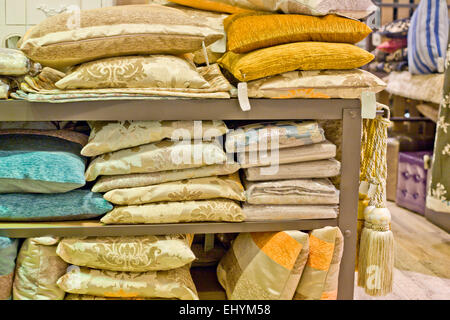 Bright pillows, plaids, blankets and other bedroom wear on shelves Stock Photo