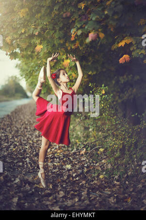 Girl doing ballet outdoors in red dress Stock Photo