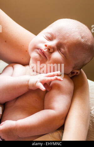 Baby boy sleeping in mother's arms Stock Photo