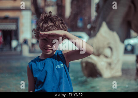Boy looking at view with hand raised to forehead, shielding eyes Stock Photo