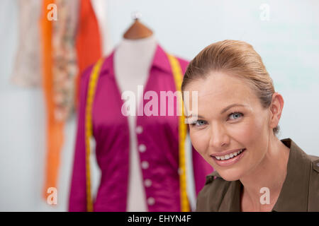 Mid adult woman looking at camera, mannequin in background Stock Photo