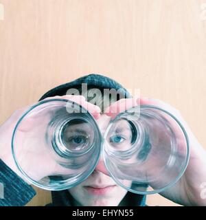 Boy looking through the bottom of two drinking glasses Stock Photo