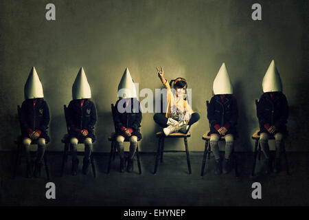 Girl in casual clothing sitting on a chair between five girls wearing uniforms Stock Photo