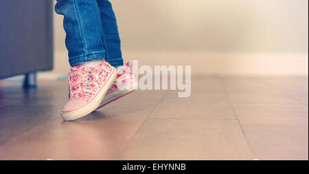 Baby girl learning to stand on her feet Stock Photo