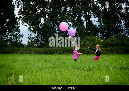 Two girls playing with balloons in a garden in summer, Poland Stock Photo