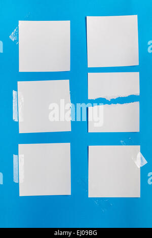 Several paper notes with sticky tape on a blue background. Stock Photo