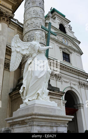 An angel statue holding a wooden cross outside the Karlskiche (St Charles) church, Vienna, Austria. Stock Photo