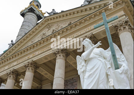 An angel statue holding a wooden cross outside the Karlskiche (St Charles) church, Vienna, Austria. Stock Photo