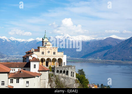 Church madonna del sasso in locarno on the mountain with an alpine lake and snow-capped mountain in background with blue sky and Stock Photo