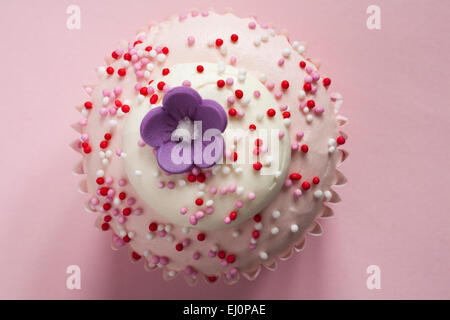 Tesco with Love strawberry and cream cupcake with flower on top isolated on pink background Stock Photo