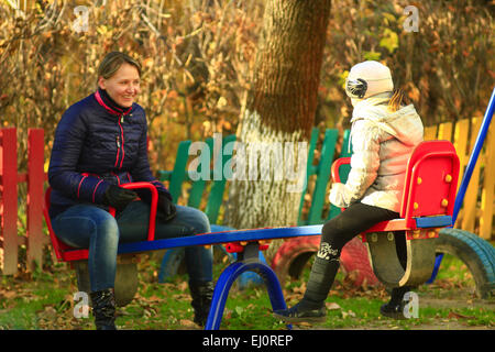 Mother with her daughter go for a drive on the swing in the park Stock Photo
