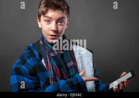 teenage boy in winter clothes holding a tablet computer Stock Photo