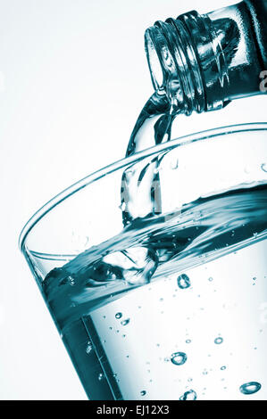 pouring water into glass from a bottle, on white background Stock Photo