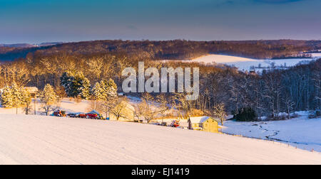 View of snow covered farm fields and rolling hills at sunset in rural York County, Pennsylvania. Stock Photo