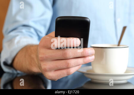 Close up of a man hand using a smart phone at breakfast with a coffee cup in the background Stock Photo