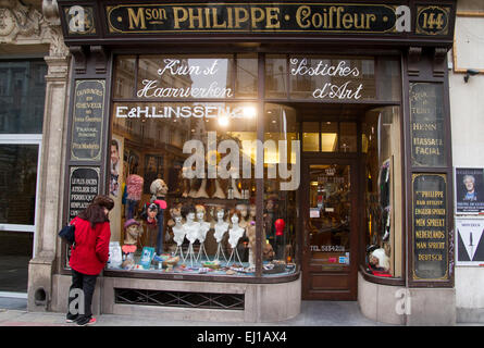 woman peers into a traditional wig shop in brussels Stock Photo