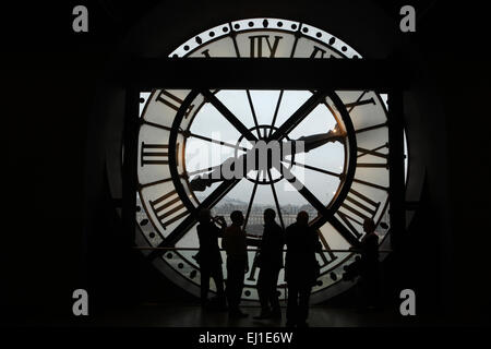 Visitors look out thought the glass clock in the Musee d'Orsay in Paris, France. Stock Photo