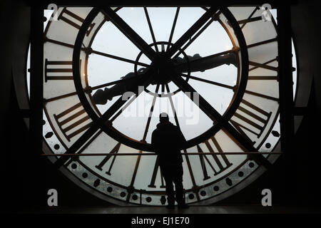Visitor looks out thought the glass clock in the Musee d'Orsay in Paris, France. Stock Photo