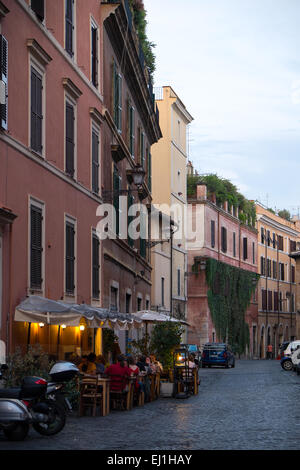 On a small side street in the Trastevere neighborhood in Rome, Italy, diners enjoy a meal outside on a warm fall evening. Stock Photo