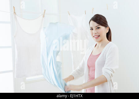 Young woman drying clothes and smiling at the camera, Stock Photo