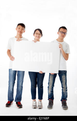 Teenagers standing and holding white board together Stock Photo