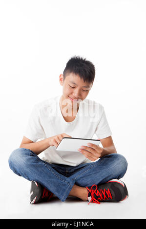 Teenage boy holding touch pad and looking down with smile Stock Photo