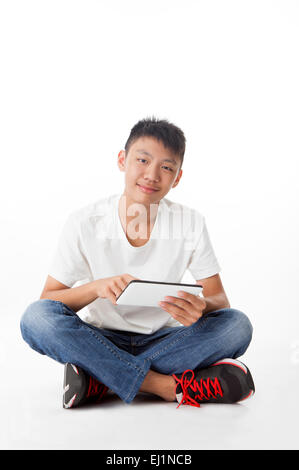 Teenage boy sitting and holding touchpad with smile Stock Photo