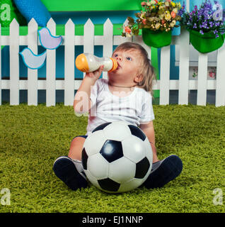 Little boy with football drinking milk from bottle with nipple Stock Photo