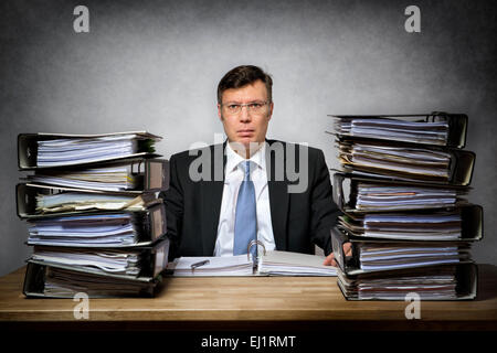Overworked depressed businessman with lot of files on his desk Stock Photo